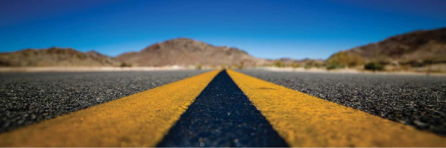 Close up image of a paved road and its yellow lane dividers