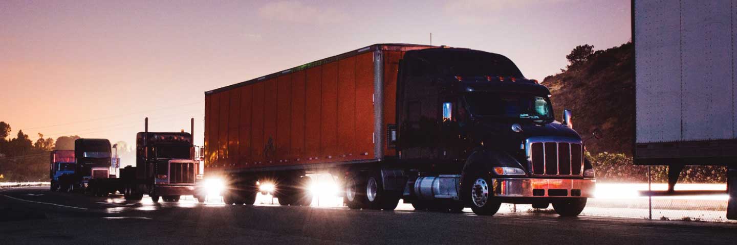 A line of trucks on a busy roadway at dusk