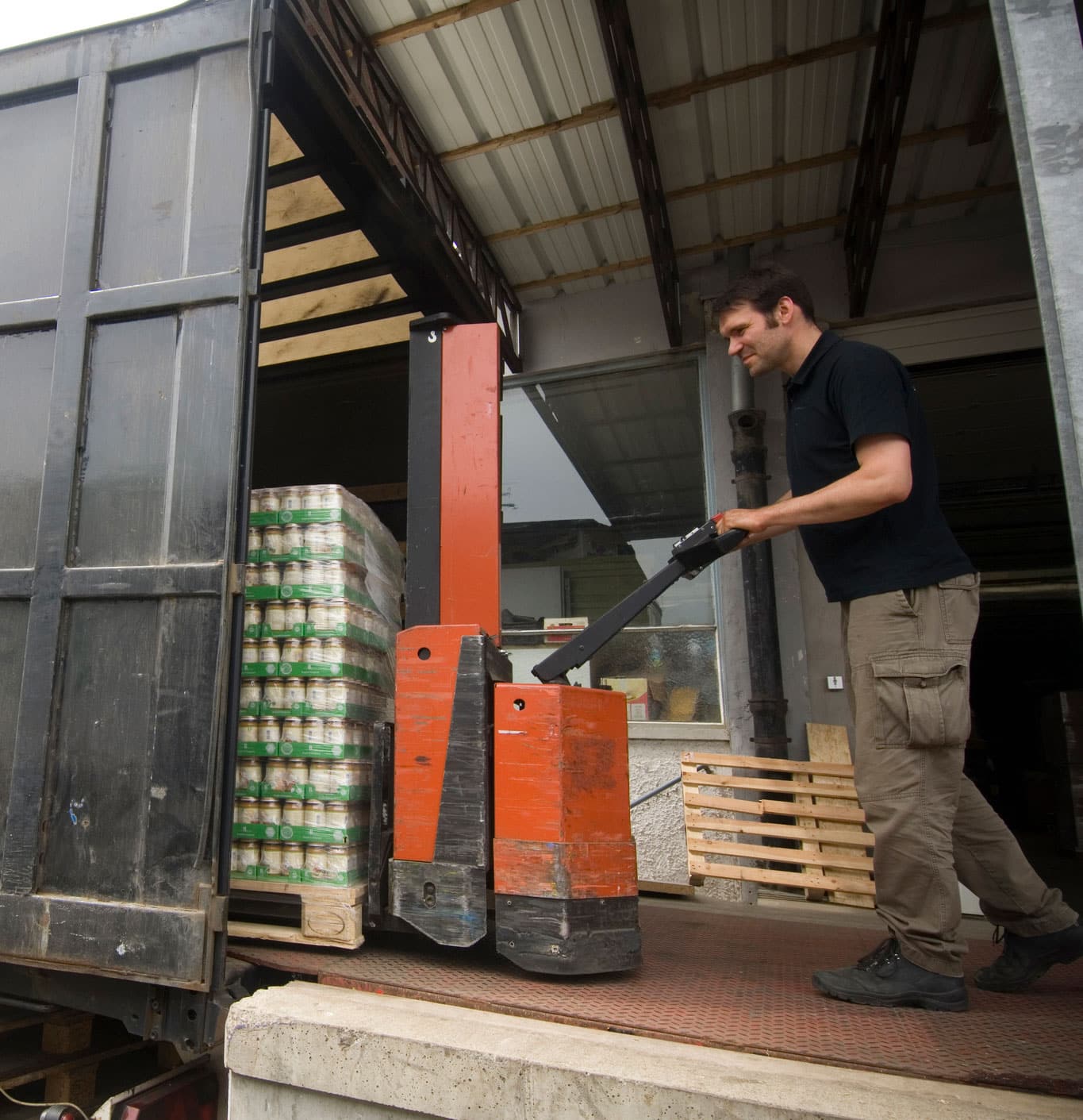 man moving pallet of canned food off truck