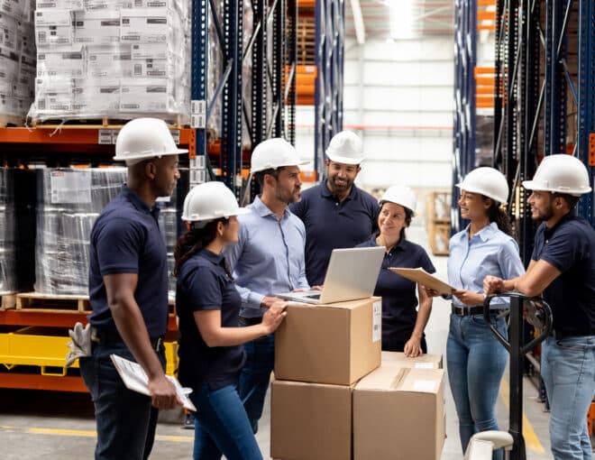 business manager talking with a group of employees inside a warehouse