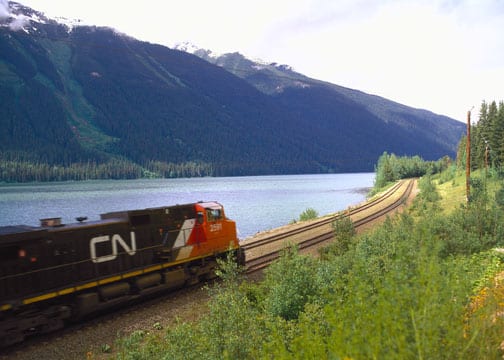 train on tracks overlooking mountains and lake