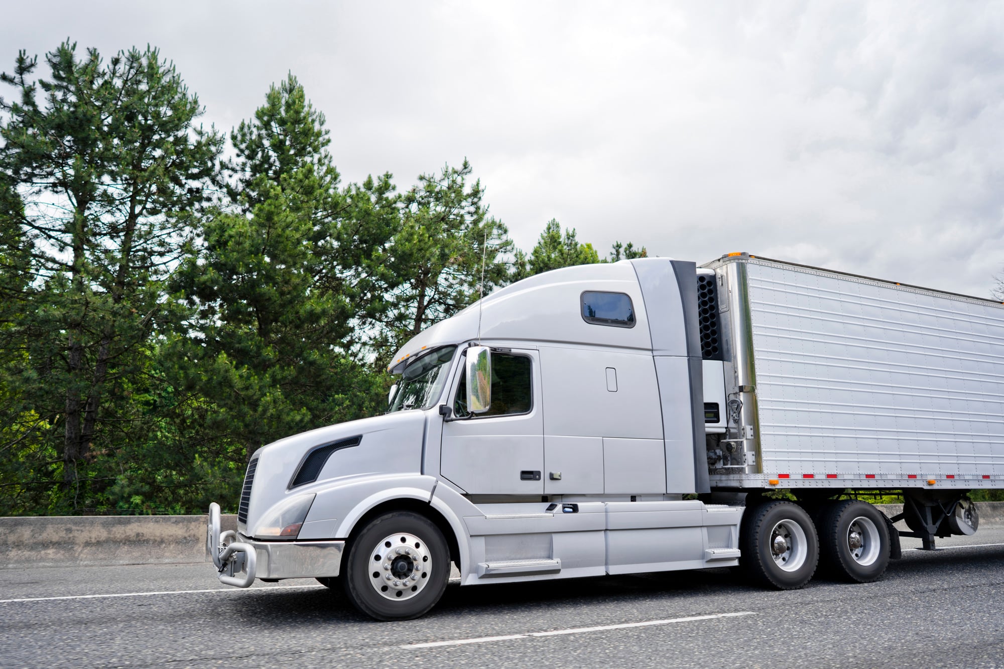 a moving Reefer Truck with green trees behind it