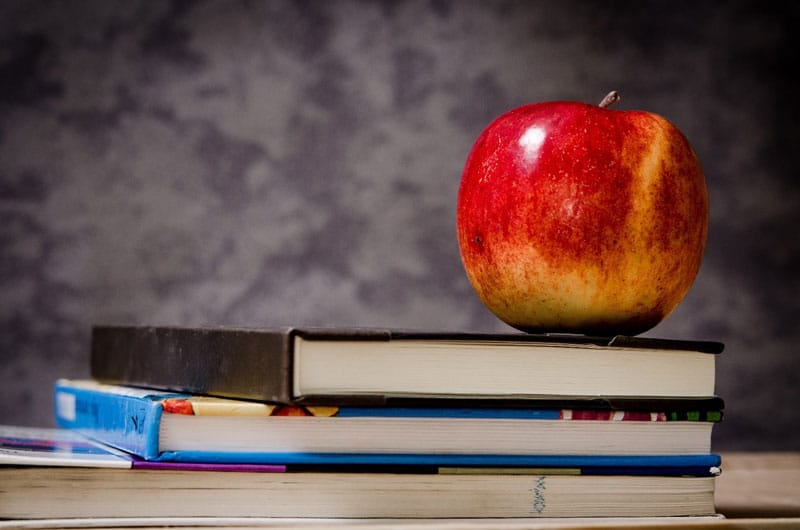 apple sitting on top of school books