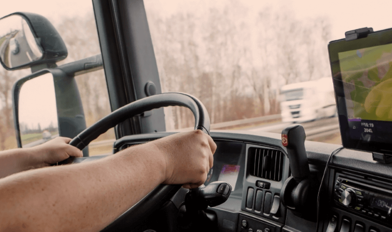 hands of semi truck driver on steering wheel