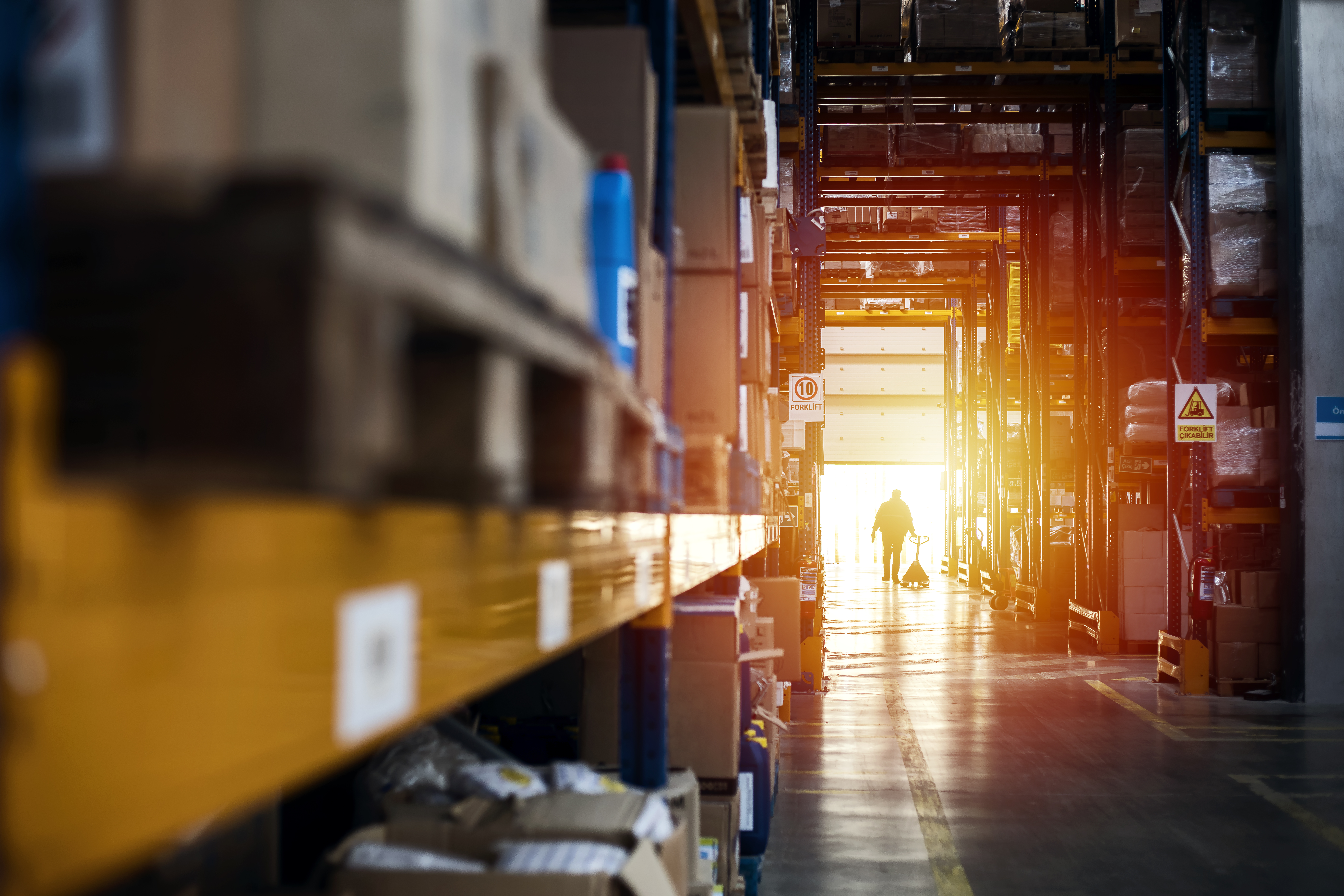 Warehouse worker transporting a forklift at sunset