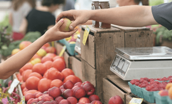 two hands exchanging produce in grocery store
