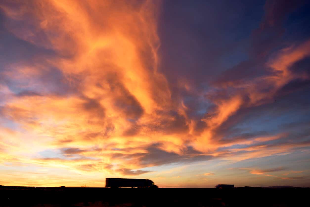 semi truck driving at sunset