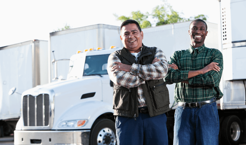 two smiling drivers in front of semi trucks