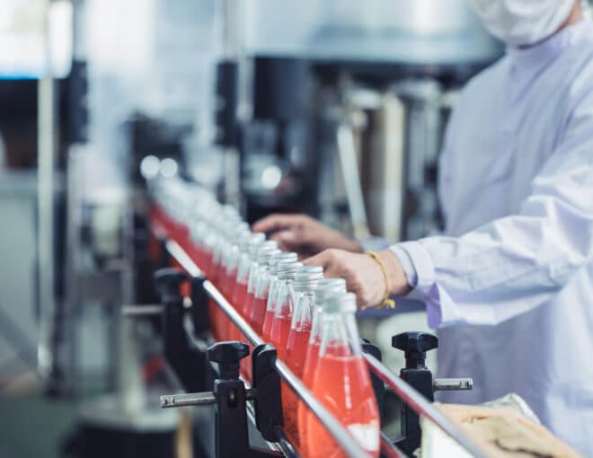 Beverage production line with a worker inspecting bottled drinks
