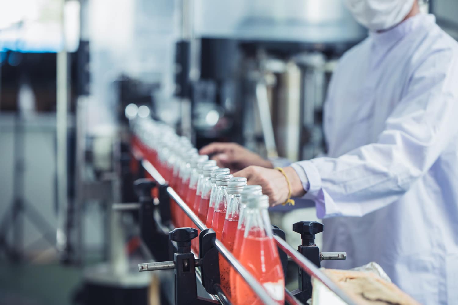 Beverage production line with a worker inspecting bottled drinks