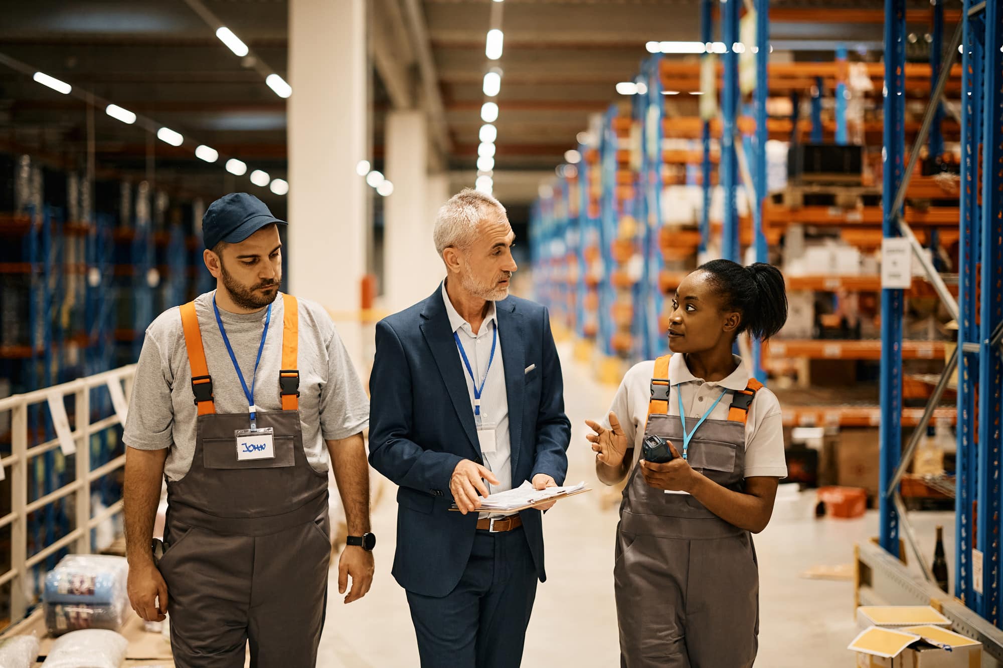 Two workers and a manager walking and talking about warehouse management