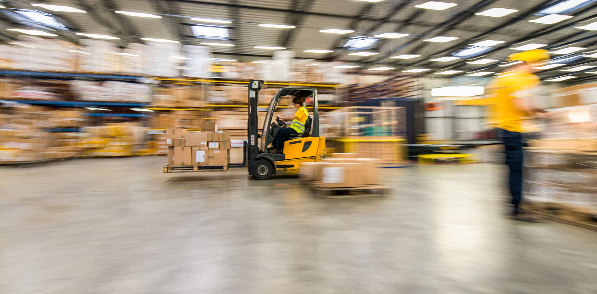 Forklift moving boxes in busy warehouse