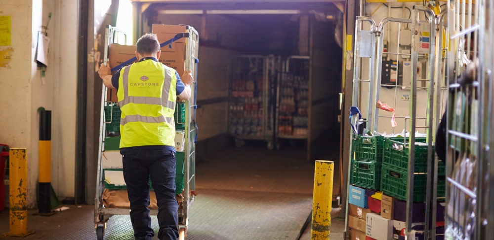 Man pushing cart into a truck at a warehouse