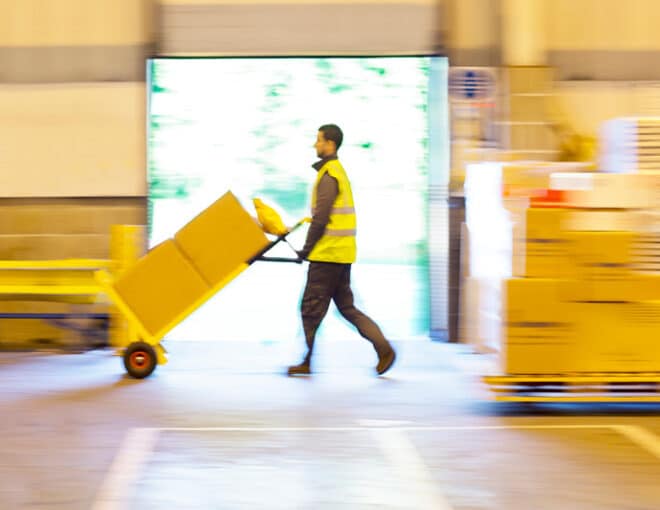 warehouse worker moving boxes on a manual forklift