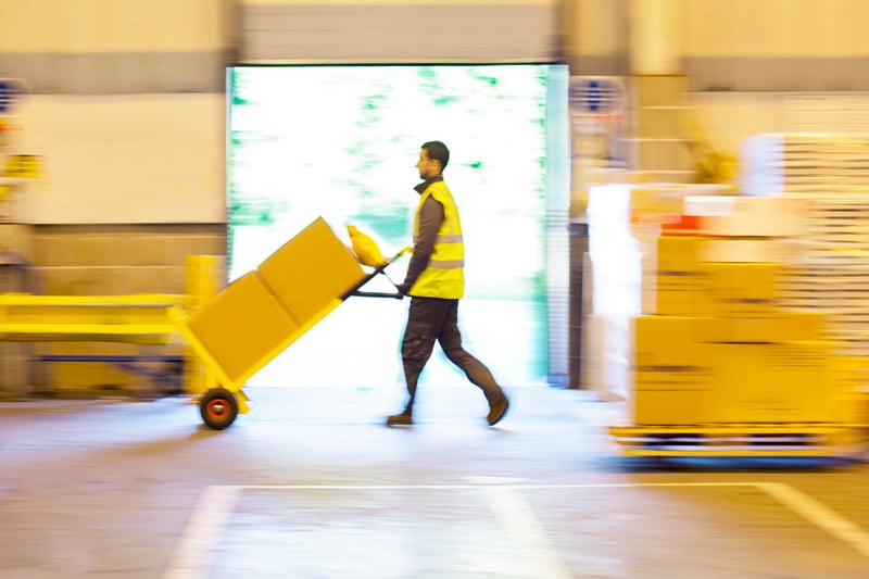warehouse worker moving boxes on a manual forklift