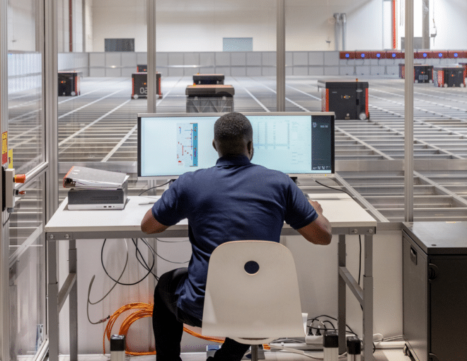Man operating parcel sorting robot system in warehouse