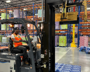 Warehouse worker performing forklift operations to move beverage pallets