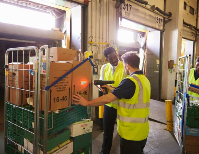 group of warehouse workers using a barcode scanner to unload freight containers