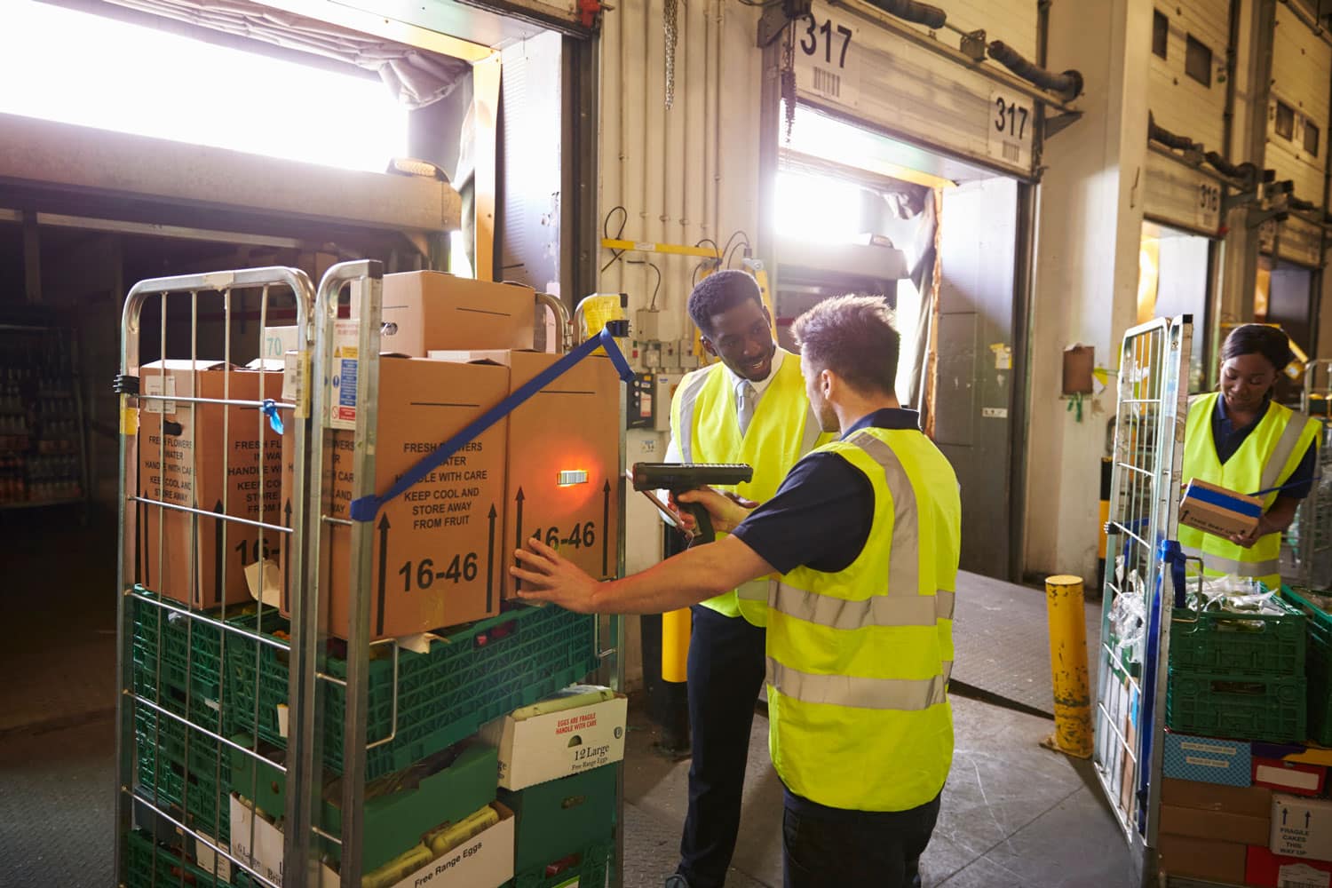 group of warehouse workers using a barcode scanner to unload freight containers