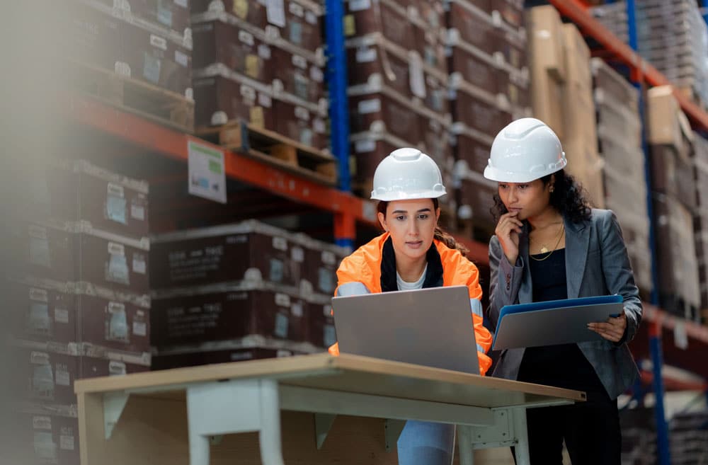 worker and supervisor meeting in front of laptop in warehouse
