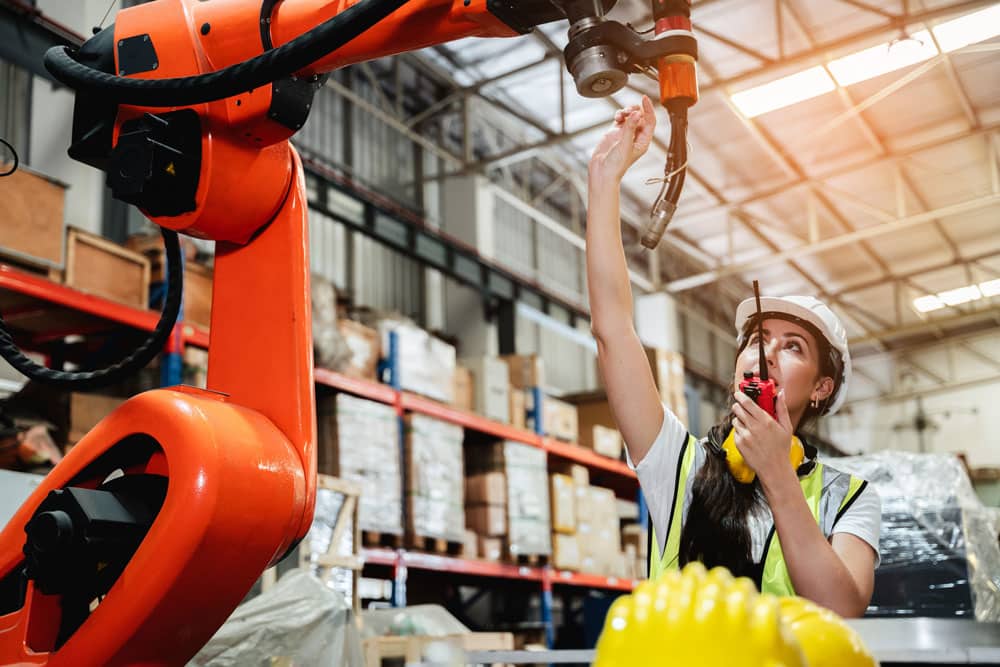 worker working on a robot in warehouse to help with automation