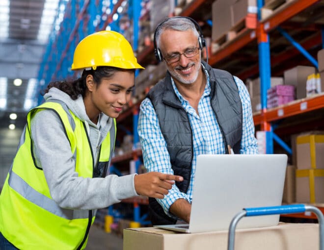 warehouse manager looking into data with the help of a worker