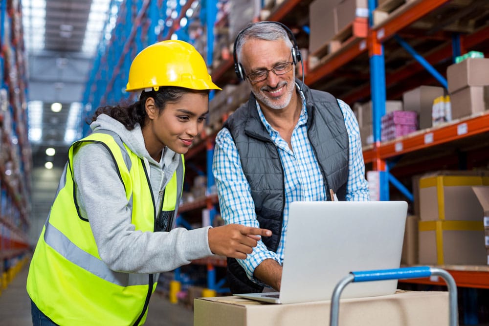warehouse manager looking into data with the help of a worker