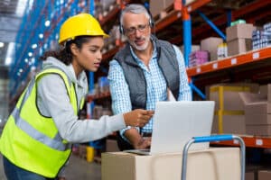 warehouse worker working on a laptop with operations manager