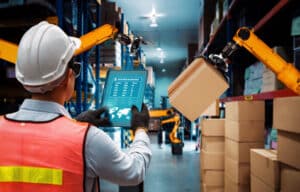 employee controlling robot arms in warehouse through automation tools