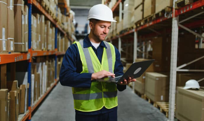 Warehouse Employee checking WMS on laptop.