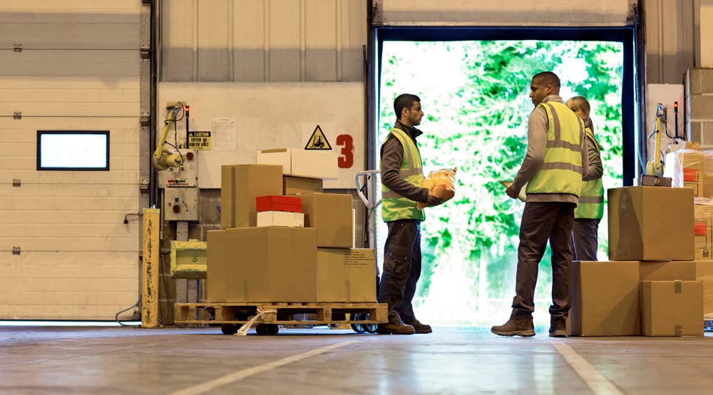 warehouse associates working together on loading dock at distribution center.