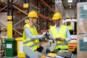 Female warehouse worker learning how to operate a forklift with an instructor