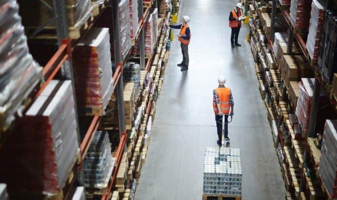 a view in to a busy warehouse with an associate pulling a manual forklift