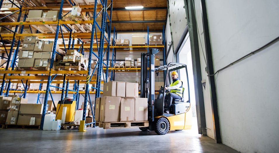 warehouse worker driving a forklift near a dock in the summer heat
