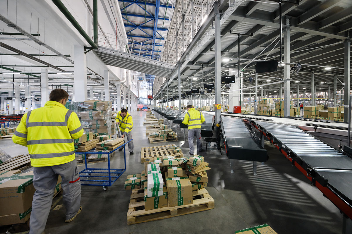 Warehouse workers performing kitting and assembly along a conveyor belt