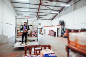 warehouse worker unloading food truck inside warehouse by forklift
