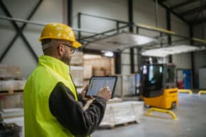 Warehouse manager checking a tablet beside a forklift at the inbound receiving dock